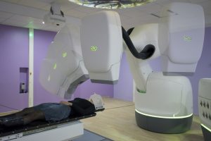Le CyberKnife est un accélérateur de particules monté sur un bras robotique inspiré de l’industrie automobile de pointe, ce qui permet de le positionner dans les meilleurs axes possibles par rapport à la zone à irradier.