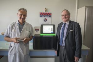 Le Pr Christophe Burucoa, chef du laboratoire de bactériologie au CHU de Poitiers, et Jean-Pierre Doury, président de Sport et collection, devant le séquenceur génomique à haut débit, un équipement acquis grâce à Sport et collection.